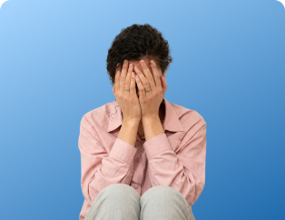 Person sitting with their face in their hands, expressing distress or frustration