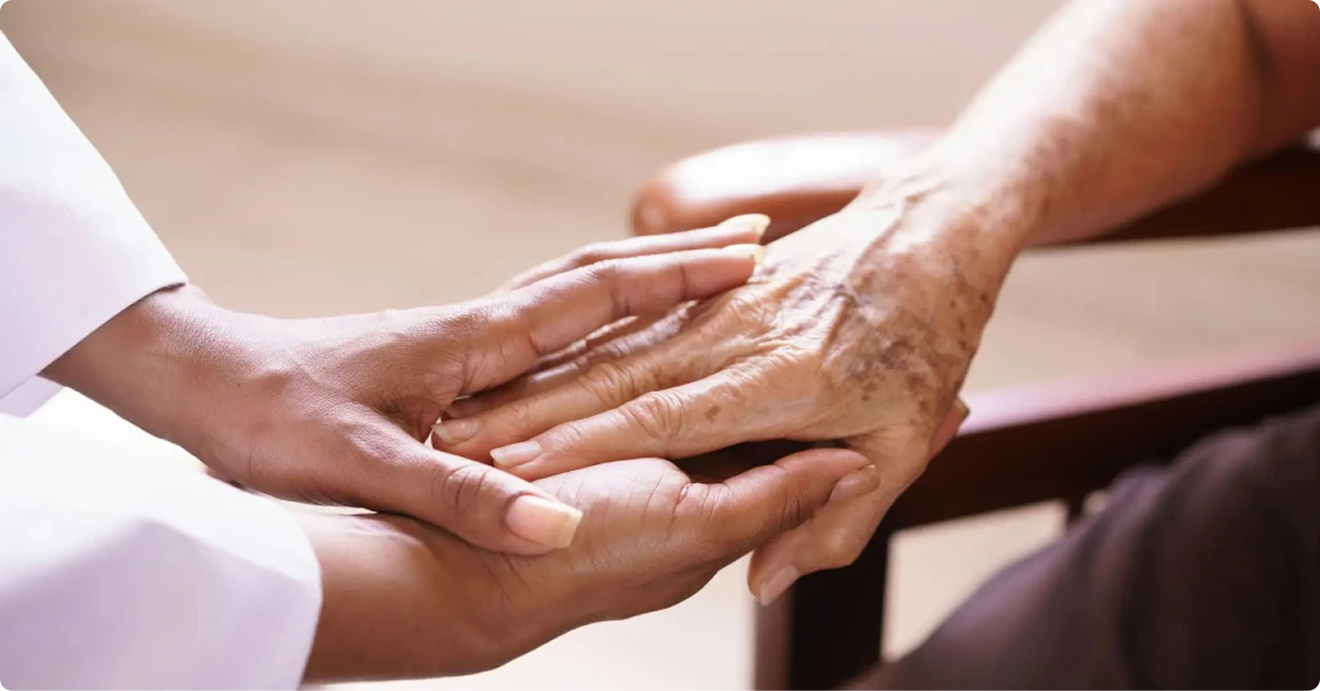 Close-up image of a caregiver's hands gently holding the hands of an elderly person, symbolizing support and compassion in elderly care.