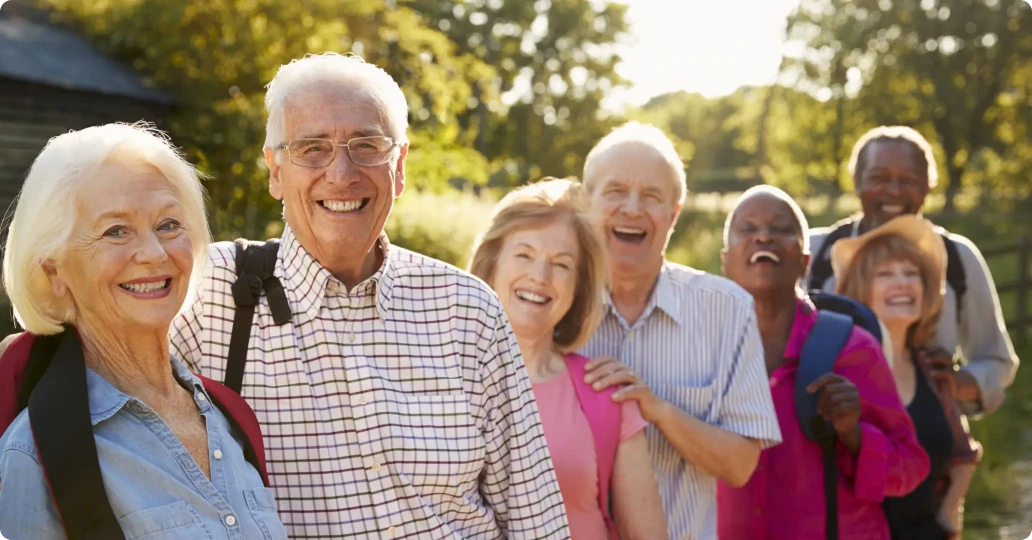 Group of joyful seniors enjoying a sunny day outdoors, laughing and walking together, showcasing active and happy aging