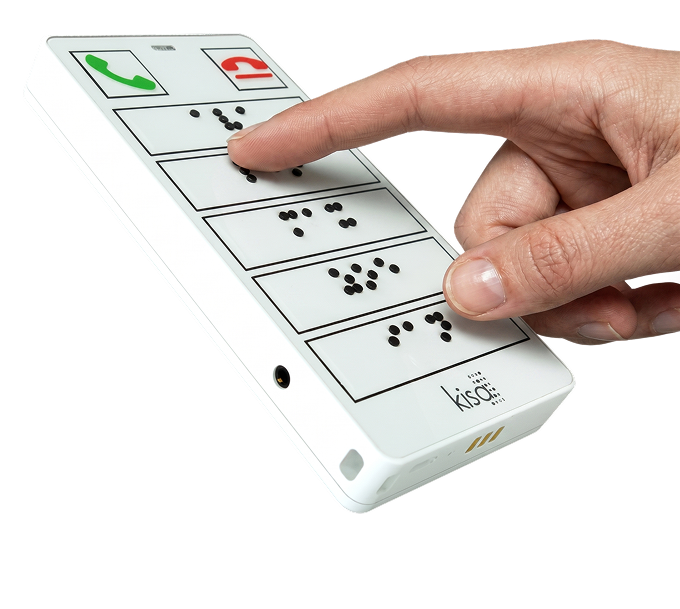 A hand pressing a button on a KISA Phone, which features braille labels on large, high-contrast buttons for easy accessibility.