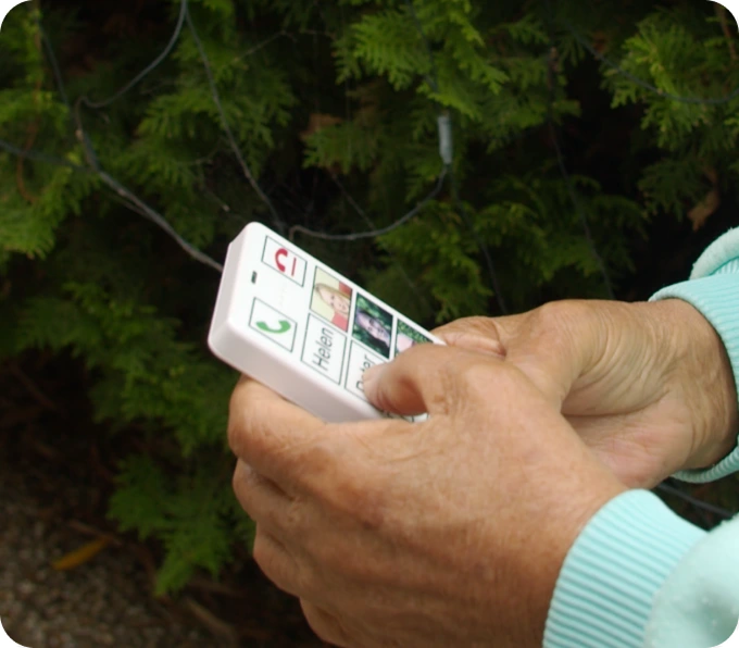 Hands holding KISA device outdoors showing fall detection technology practical use for elderly safety independence